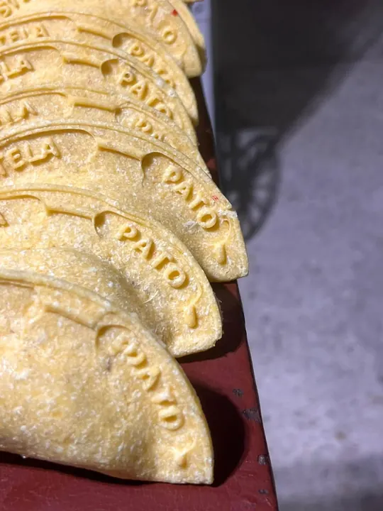 Empanadas apiladas, cada una con el relleno grabado en el borde.