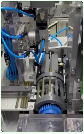 Mecanismo de alimentación montado en la máquina, con actuadores neumáticos, mangueras y guías lineales.